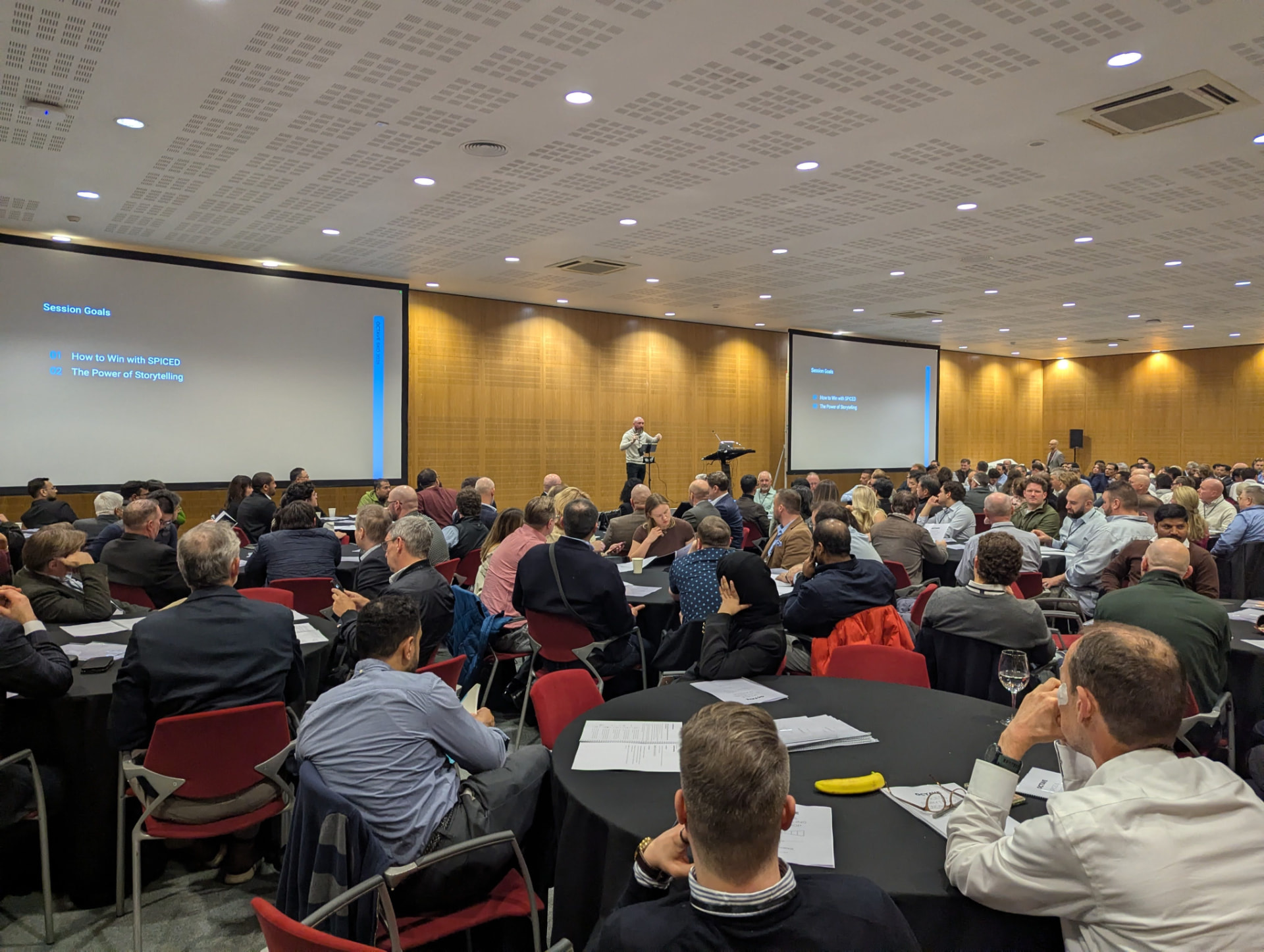 Shane McGrath facilitating a room of participants seated at round tables
